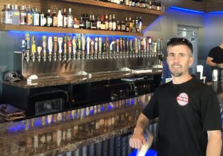 Bar technician posing beside stainless multi-tap setup